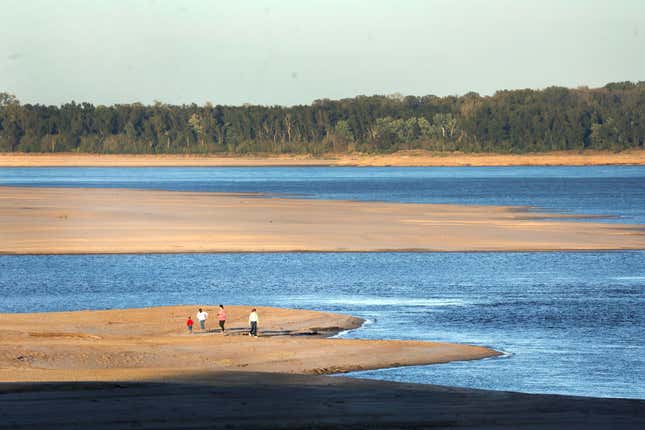 People walk across a sand bar exposed by low water on the Mississippi River on October 19, 2022 in Helena, Arkansas. 