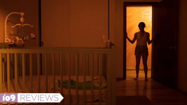 A woman stands silhouetted in a doorway, with a baby's crib in the foreground