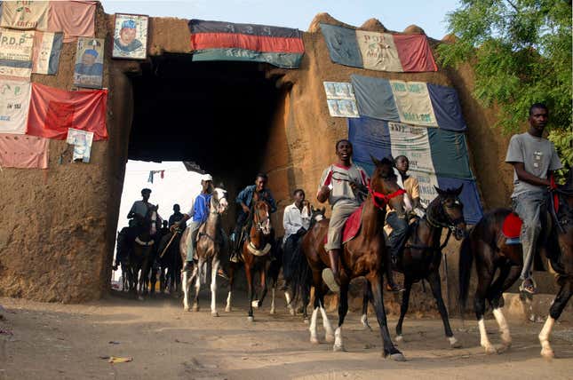 Horsemen exit one of the old gates in the ancient wall of Kano’s old town, decorated with political parties’ flags, in 2007.