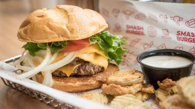 A burger from Smashburger in a basket next to some fries