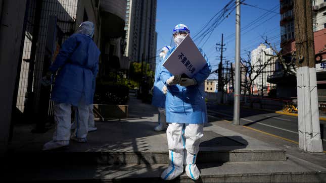 People in protective suits hold signs in Shanghai.