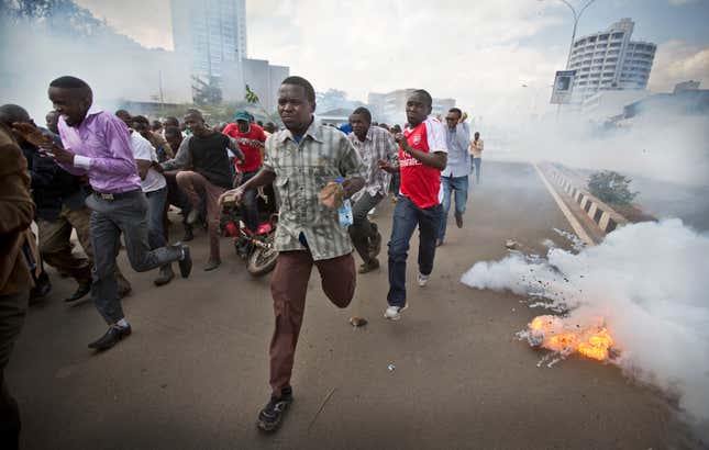Opposition supporters, some carrying rocks, flee from exploding tear gas grenades fired by riot police in March 2016.