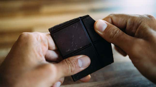 Hands holding piece of chocolate bar