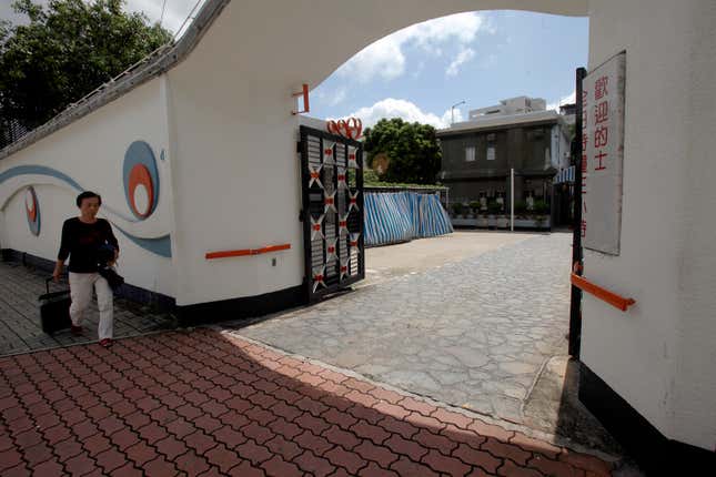 A woman walks past the former Kowloon Tong home of kung fu star Bruce Lee, at the time a motel frequented by couples. The billionaire owner’s death has left the property in dispute among his heirs—and in danger of being demolished.
