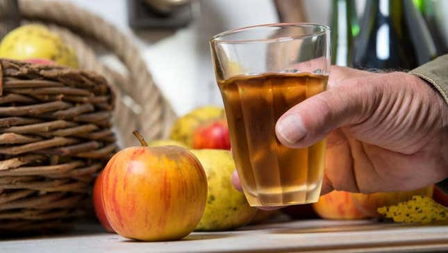 glass of apple cider held beside apples