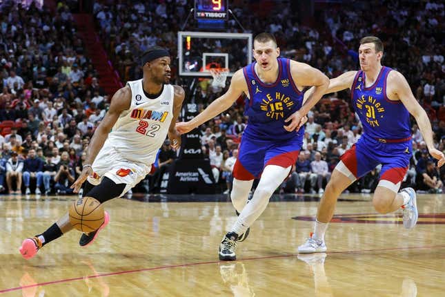 Miami Heat forward Jimmy Butler (22) dribbles the basketball ahead of Denver Nuggets center Nikola Jokic (15) and forward Vlatko Cancar (31) during the second quarter at Miami-Dade Arena.