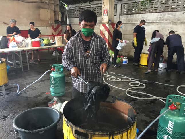 Clothes are dyed black, the color worn by Thais mourning the death of Thailand's King Bhumibol Adulyadej, by members of Krung Thai Tractor, a tractor and heavy machinery importing company, at the free dying station in Bangkok, Thailand, Monday, Oct. 17, 2016. Pop-up clothes dyeing centers are a new phenomenon in the Thai capital as black apparel becomes too expensive for many following the king's death. The Thai government has declared national mourning for Bhumibol, who died Thursday, and some clothing sellers have been quick to hike prices for black garments. Others have run out of stock. (AP Photo/Natnicha Chuwiruch)