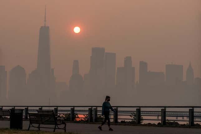 A woman walks with the New York skyline in the background.