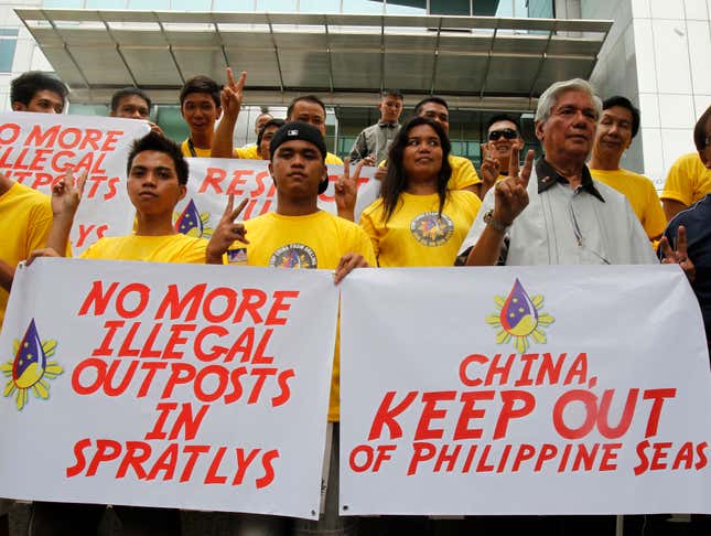 A Filipino-American group flashes peace signs during a protest in front of the Chinese consulate building in Manila on July 8, 2011.