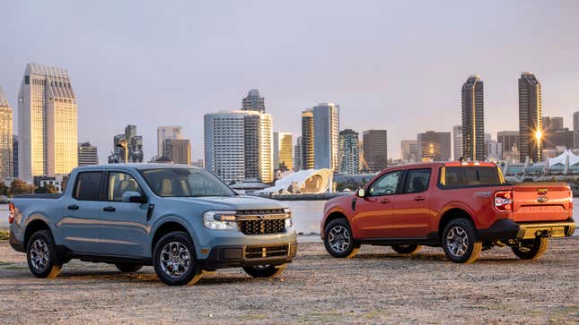 A photo of two Ford Maverick pickups parked with a city behind them. 