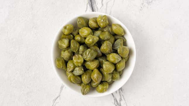 Bowl of capers on white marble countertop