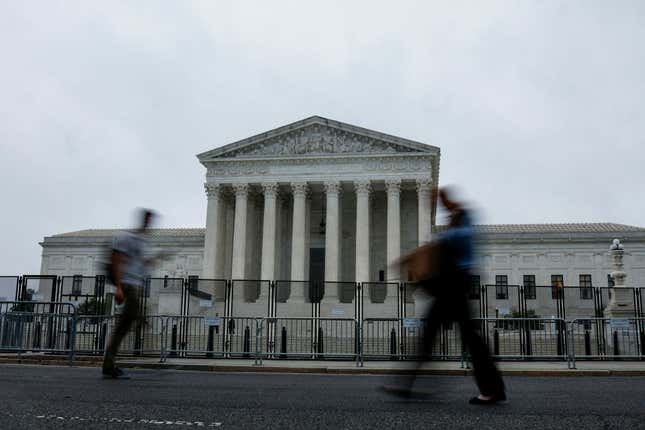 People walk past the U.S. Supreme Court Building during a rainstorm on June 23, 2022, in Washington, DC. Decisions are expected in 13 more cases before the end of the Court’s current session.
