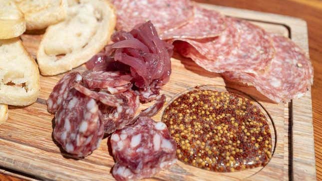 Close-up view of a charcuterie board with meat, bread, and mustard
