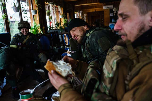 MMA fighter Yaroslav Amosov, resting his head on this hands, with his fellow Ukrainian soldiers.