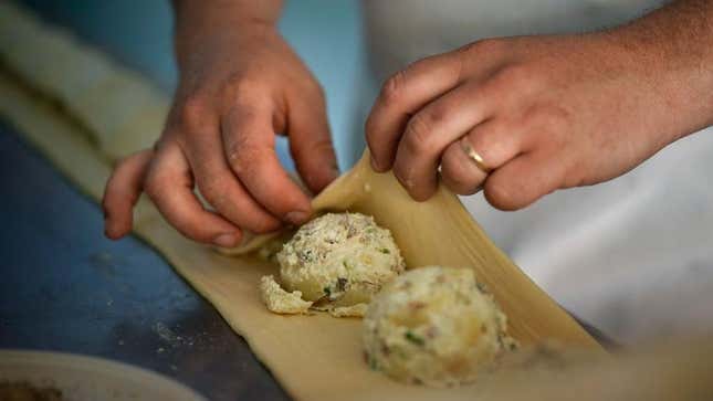 Person's hands folding knish