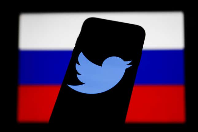 A phone with the Twitter logo on it in front of the Russian flag.
