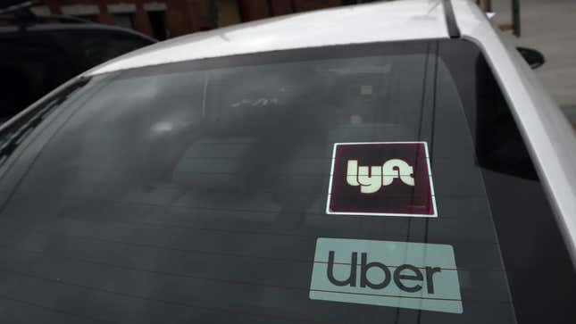 Car windshield featuring a Lyft and Uber sticker on the windshield.