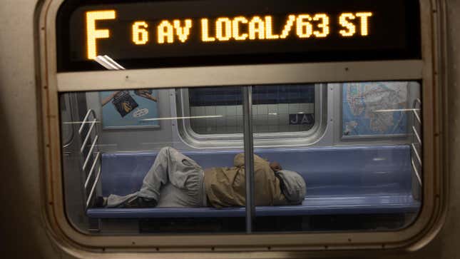 A homeless man sleeps on a northbound F train, March 31, 2023, in Brooklyn, New York. 
