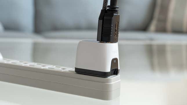 The Human Things Genki Covert Dock Mini plugged into a power bar, with an HDMI and USB-C cable attached.