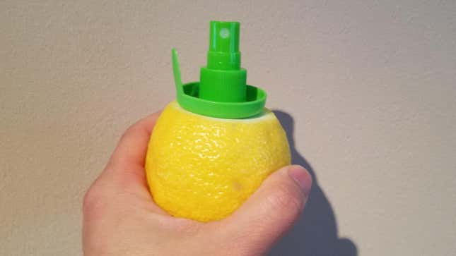 Hand holding a lemon into which a Stem Citrus Sprayer attachment has been screwed