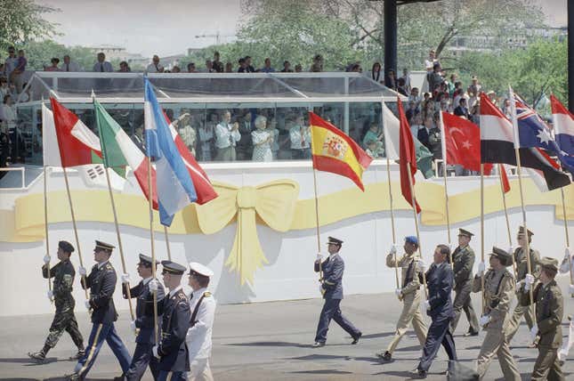 Soldiers of the allied coalition carry their national flags past the reviewing stand and President Bush in Washington on Saturday, June 8, 1991 during the National Victory Parade.