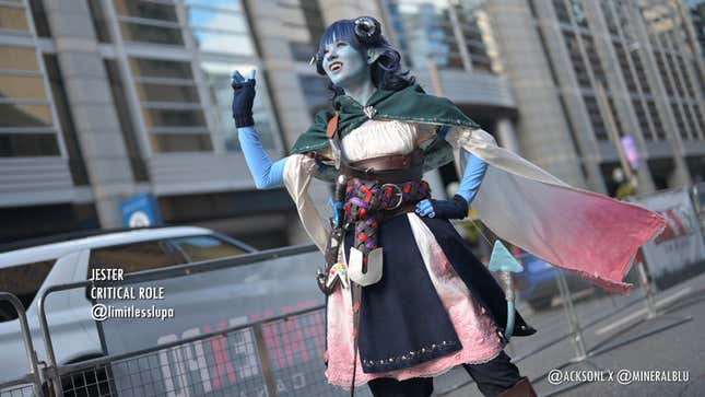 A cosplayer dressed as Jester from Critical Roll stands outside with their pink-tinged shirt sleeves billowing in the wind. 