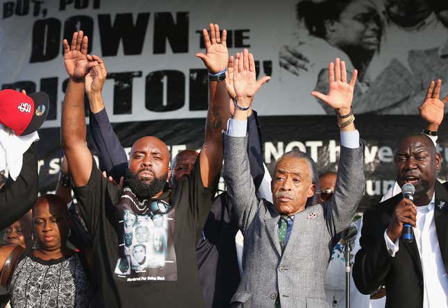 Michael Brown Sr. (L) and Civil rights leader Rev. Al Sharpton (2nd from left) hold up their hands as attorny Benjamin Crump (R) speaks at Peace Fest music festival in Forest Park on August 24, 2014 in St. Louis, Missouri. Brown is the father of Michael Brown who was shot and killed by a police officer in nearby Ferguson, Missouri on August 9. Michael will be buried tomorrow
