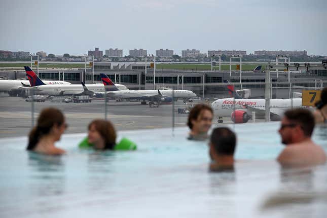 With parked aircraft in the background, people take a dip in the heated infinity pool of the TWA Hotel at JFK International Airport, in the Queens borough of New York City, NY, June 13, 2021. Set in the former TWA flight center designed by architect Eero Saarinen and opened in 2019, the hotel evokes an architectural style of the 1960&#39;s.