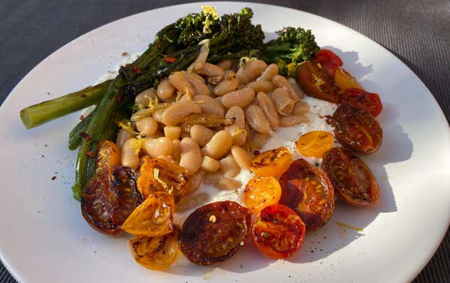 Cherry tomatoes, beans, and broccolini arranged in stripes over a bed of ricotta