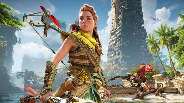 Aloy stands on a beach in front of a bombed out overgrown tower in post apocalypse San Francisco in Horizon Forbidden West.