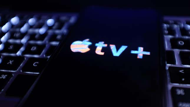A phone with the apple TV+ logo sitting on top of a macbook keyboard.