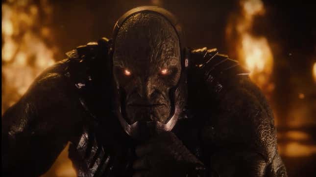 Darkseid strokes his chin in thought while lava bursts behind him.