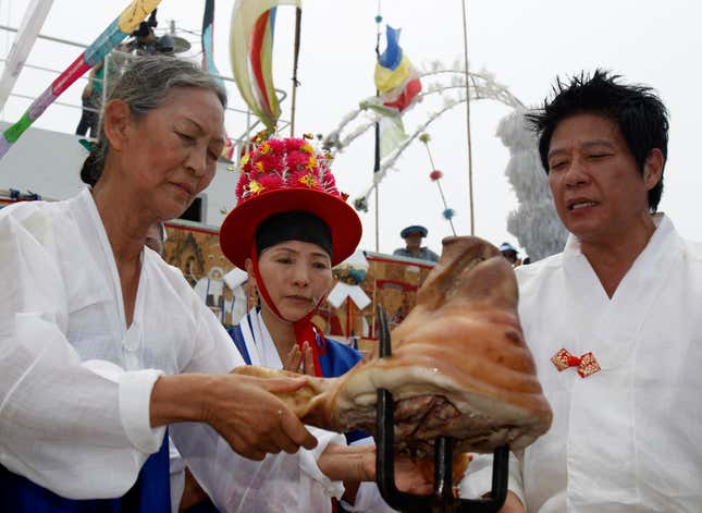 South Korean shamans perform prayers in front of a pig’s head that is poked onto a trident, during a shipboard ceremony intended to exorcise the demons that threaten fishermen and to bring good luck to everybody on board. June 24, 2012.
