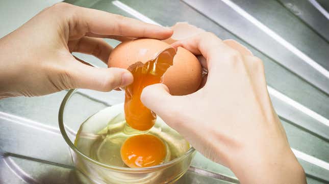 Stock photo of hands cracking egg into bowl