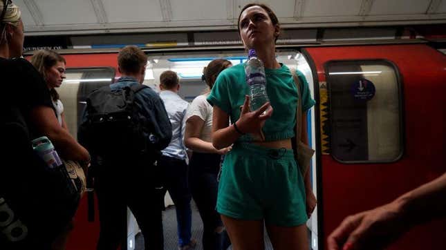 A commuter carries a bottle of water as they exit the carriage of a London Underground tube train in central London, on July 19, 2022 as the country experiences an extreme heat wave.
