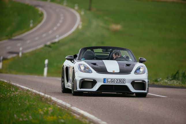 A 2024 Porsche 718 Spyder RS with Weissach Package drives towards you on a curving country road.