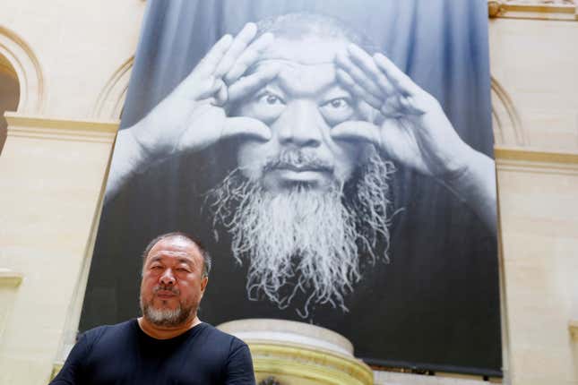 Ai Weiwei poses under the poster of an exhibition titled "Ai Weiwei: By the way, it's always the others" in Switzerland.