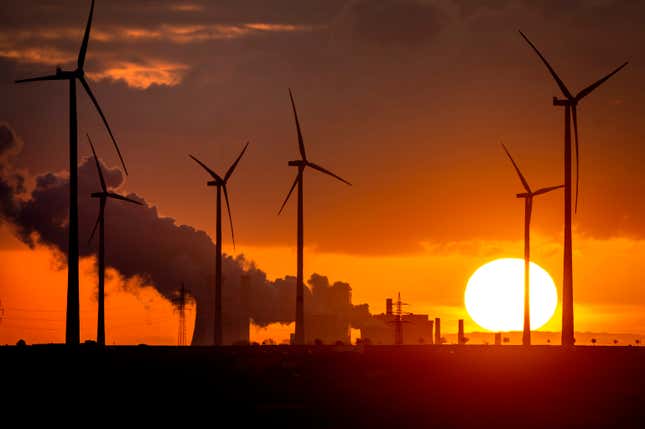 The sun rises behind steam coming from a coal-fired power plant and wind turbines in Niederaussem, Germany in November 2022. 