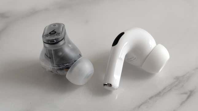 A single Beats Studio Buds + earbud next to a single Apple AirPods Pro 2 earbud.