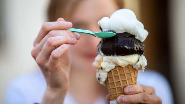 Person eating an ice cream cone with a spoon