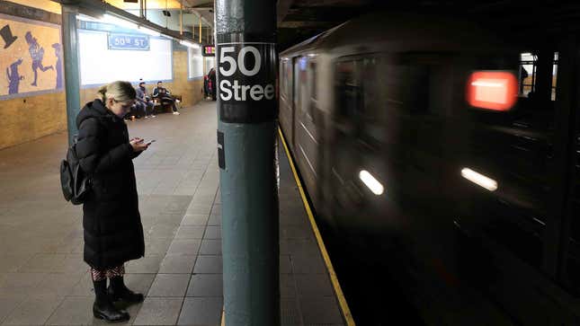 A commuter holds a cell phone on the platform for the 50th St. station on the 1 line in the NYCT subway.