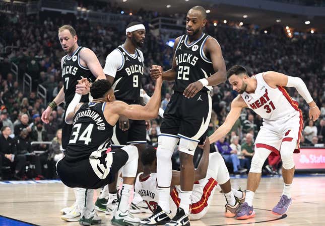 Apr 16, 2023; Milwaukee, Wisconsin, USA; Milwaukee Bucks forward Giannis Antetokounmpo (34) is helped up after a collision in the first half against Miami Heat center Bam Adebayo (13) during game one of the 2023 NBA Playoffs at Fiserv Forum.