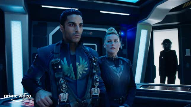 An intense-looking man and woman in military spacesuits stand on the bridge of a ship in a scene from The Expanse.