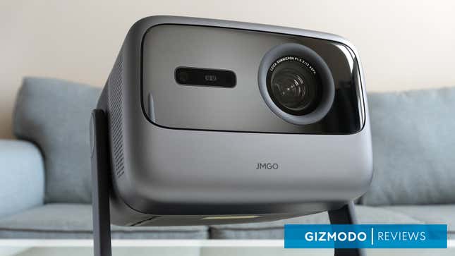 A close-up of the front of the JMGO N1 Ultra projector with a sofa behind it.