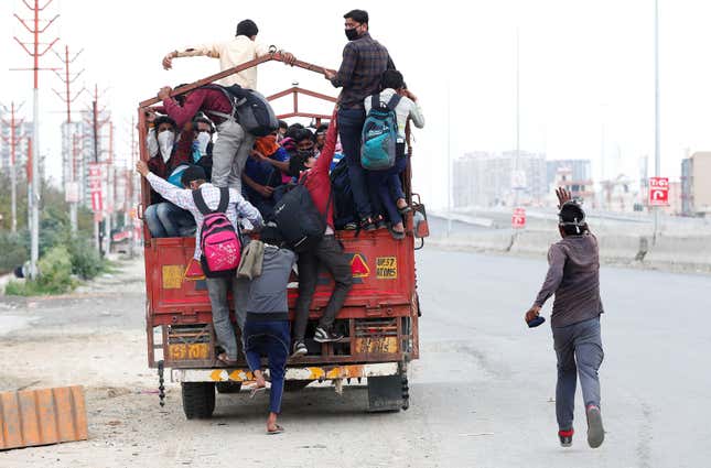 A migrant worker runs behind a truck as others try to board it to return to their villages.