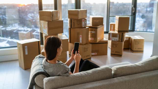 Woman using smartphone by stacks of moving boxes