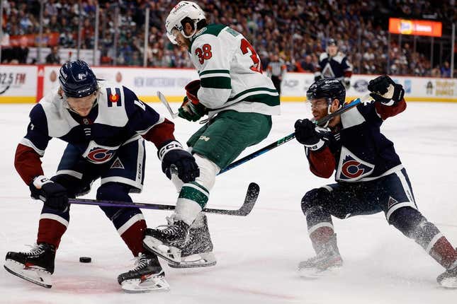 Mar 29, 2023; Denver, Colorado, USA; Minnesota Wild right wing Ryan Hartman (38) plays the puck through Colorado Avalanche defenseman Bowen Byram (4) and left wing J.T. Compher (37) in the first period at Ball Arena.