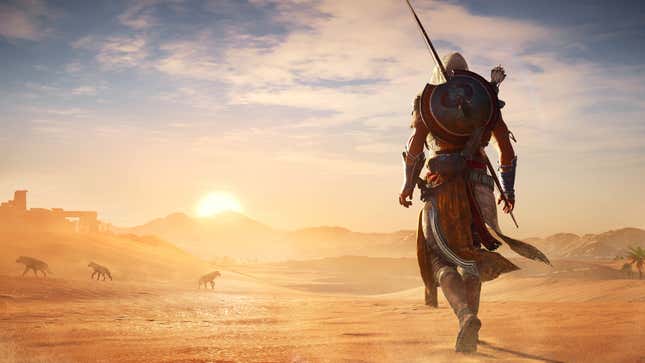 Bayek walks toward sand dunes at sunset in Assassin's Creed Origins.