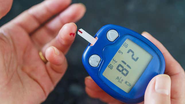 A woman using a blood sugar monitor.