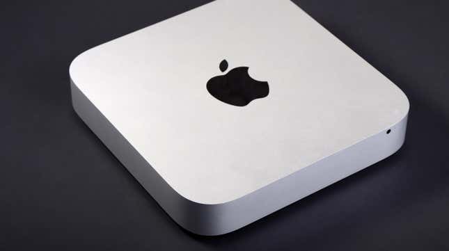 An Apple M2 Mac Mini sitting on a black table.